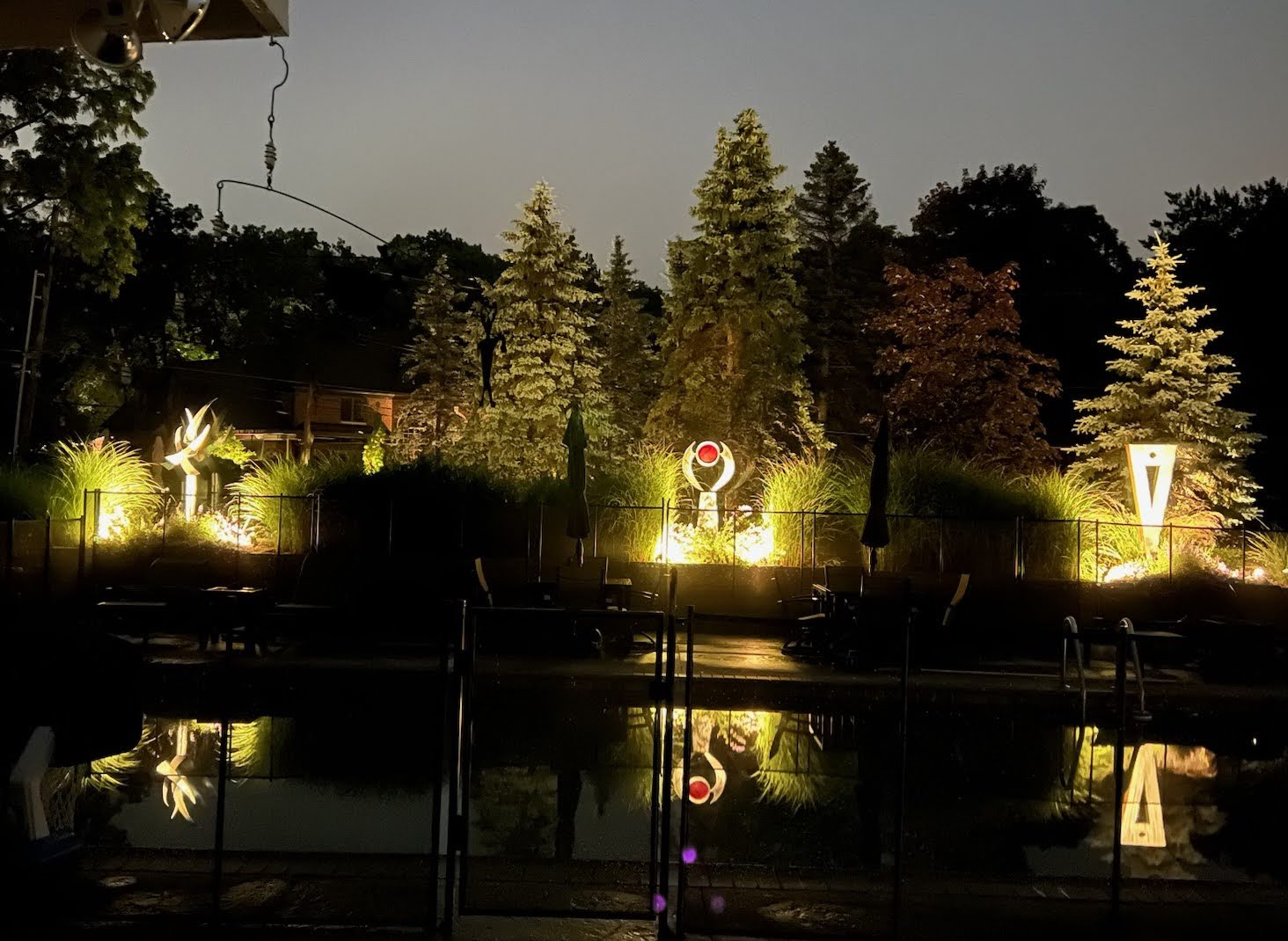 Original metal sculptures illuminated in a landscaped outdoor setting
